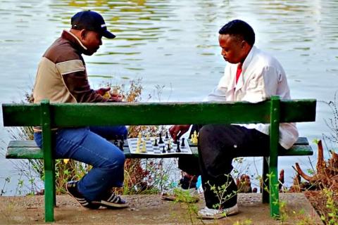 Two men are playing chess on a bench.. The Thai for "Two men are playing chess on a bench." is "ผู้ชายสองคนกำลังเล่นหมากรุกบนม้านั่ง". Two men are playing chess on a bench.. The Thai for "Two men are playing chess on a bench." is "ผู้ชายสองคนกำลังเล่นหมากรุกบนม้านั่ง".