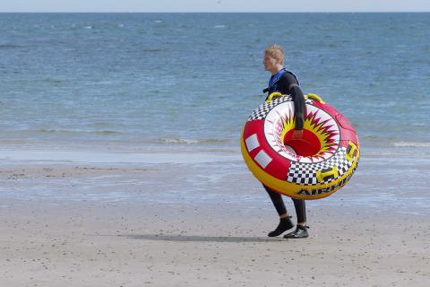 A man is carrying a rubber ring at the beach. The Thai for "a man is carrying a rubber ring at the beach" is "ผู้ชายถือห่วงยางที่ชายหาด". A man is carrying a rubber ring at the beach. The Thai for "a man is carrying a rubber ring at the beach" is "ผู้ชายถือห่วงยางที่ชายหาด".