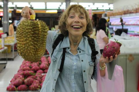 A woman is holding a durian and a dragon fruit.. The Thai for "A woman is holding a durian and a dragon fruit." is "ผู้หญิงถือทุเรียนและแก้วมังกร". A woman is holding a durian and a dragon fruit.. The Thai for "A woman is holding a durian and a dragon fruit." is "ผู้หญิงถือทุเรียนและแก้วมังกร".