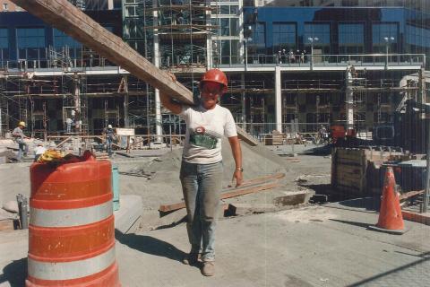 A female worker carrying a wooden beam. The Thai for "a female worker carrying a wooden beam" is "คนงานหญิงแบกเสาไม้". A female worker carrying a wooden beam. The Thai for "a female worker carrying a wooden beam" is "คนงานหญิงแบกเสาไม้".