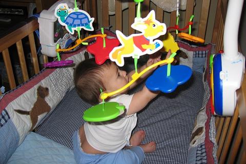 A baby playing with a mobile. The Thai for "a baby playing with a mobile" is "ทารกเล่นโมบาย". A baby playing with a mobile. The Thai for "a baby playing with a mobile" is "ทารกเล่นโมบาย".