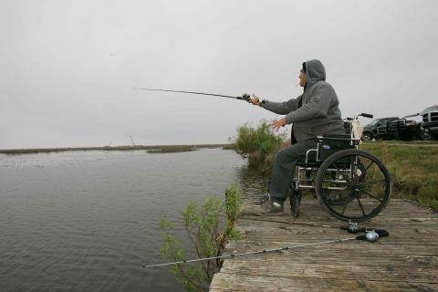 A man sitting in a wheelchair while fishing. The Thai for "a man sitting in a wheelchair while fishing" is "ผู้ชายนั่งอยู่ในวีลแชร์ขณะตกปลา". A man sitting in a wheelchair while fishing. The Thai for "a man sitting in a wheelchair while fishing" is "ผู้ชายนั่งอยู่ในวีลแชร์ขณะตกปลา".